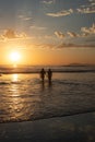 Silhouette view of two people walking out of the water at sunset Royalty Free Stock Photo