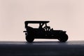 Silhouette of a vintage jeep toy on a table against a white background