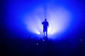 silhouette of a vocalist and microphone stand on stage in a blue haze. Royalty Free Stock Photo