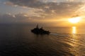 Silhouette of warship sails in the sea with golden light brace upon the sea surface