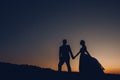 Silhouette of the wedding couple, the groom and the bride, holding hands on the background of the sunset. Cute girls in Royalty Free Stock Photo