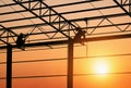 Silhouette of 2 welders welding roof metal structure of warehouse building in construction site at sunset time Royalty Free Stock Photo