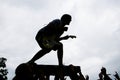 Silhouette of a wild rock guitarist crowdsurfing on a guitar case