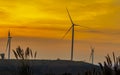 Silhouette wind turbine farm over moutain with orange sunset and Royalty Free Stock Photo