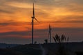 Silhouette wind turbine farm over moutain with orange sunset and Royalty Free Stock Photo