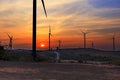 Silhouette wind turbine farm over moutain with orange sunset and Royalty Free Stock Photo