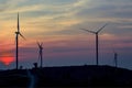 Silhouette wind turbine farm over moutain with orange sunset and Royalty Free Stock Photo