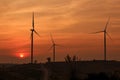 Silhouette wind turbine farm over moutain with orange sunset and Royalty Free Stock Photo