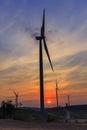 Silhouette wind turbine farm over moutain with orange sunset and Royalty Free Stock Photo