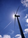 Silhouette of wind turbine with jet aircraft vapour trail Royalty Free Stock Photo