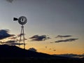 Silhouette of a windmill against a orange sunset.