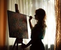 Silhouette woman artist drawing paint picture on easel indoors Royalty Free Stock Photo