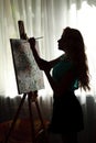 Silhouette woman artist draws paint picture on easel Royalty Free Stock Photo