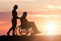 Silhouette Of Woman Assisting Her Disabled Father On Wheelchair