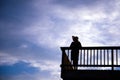 Silhouette of woman awesome shape in hat standing on balcony on Royalty Free Stock Photo