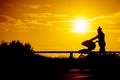 Silhouette of woman with baby stroller walking on beach at sunset Royalty Free Stock Photo