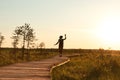 Silhouette of woman with backpack on hiking trail in summer outdoors. Naturalist enjoys nature and a moment at sunset walking on Royalty Free Stock Photo