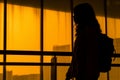 silhouette of a woman with a backpack standing in front of a window