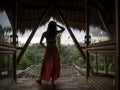 A Silhouette woman in bamboo tropical house open the door to see the views.