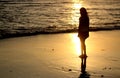 Silhouette of a woman on the beach at sunset. A girl standing alone looking at the golden sunset light view over the sea.