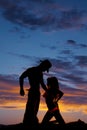 Silhouette of a woman in a bikini kneel side kiss up to cowboy