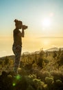 Silhouette of woman with camera. Woman takes photo of La Gomera Island in the rays of the setting sun. Tenerife Island Royalty Free Stock Photo