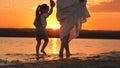 Silhouette of a woman and a child on beach at sunset. Happy family, Mom walks with child barefoot on water, joining Royalty Free Stock Photo