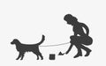 Silhouette of woman cleaning after a golden retriever dog.