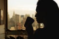 Silhouette of woman with cup of tea in the apartment with New York city view