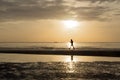 Silhouette of woman doing a brisk walking on the beach at sunset