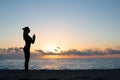 Silhouette of woman doing greeting to the sun on the beach at sunrise, morning yoga