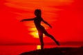 Silhouette of woman doing yoga meditation during sunset with natural golden sunlight on sea