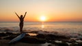 Silhouette of woman. Excited young woman raising arms at the beach in front of the ocean. View from back. Sunset at the beach. Royalty Free Stock Photo