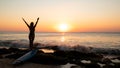 Silhouette of woman. Excited young woman raising arms at the beach in front of the ocean. View from back. Sunset at the beach. Royalty Free Stock Photo