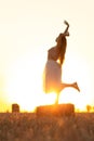 Silhouette woman figure at sunset standing on hay stack, beautiful romantic girl posing outdoors in field, freedom concept