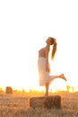 Silhouette woman figure at sunset standing on hay stack, beautiful romantic girl with long hair posing outdoors in field