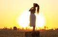 Silhouette woman figure at sunset standing on hay stack, beautiful romantic girl with long hair posing outdoors in field