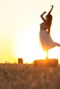 Silhouette woman figure at sunset standing on hay stack, beautiful romantic girl posing outdoors in field, freedom concept Royalty Free Stock Photo