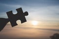 Silhouette of Woman hand holding jigsaw puzzle piece against sunrise, Business solutions, targSilhouette of business woman hand Royalty Free Stock Photo