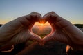 Silhouette woman hand in shape of love heart with sunrise. Fresh start of Valentine