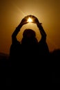 Silhouette of woman hands holding sun in triangle on background Royalty Free Stock Photo