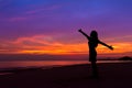 Silhouette of woman with hands up while standing on sea beach at Royalty Free Stock Photo