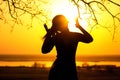 Silhouette of a woman in headphones, the girl enjoying music on the sunset
