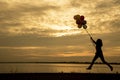 Silhouette woman holding air balloons standing and see the lake on the sunset Royalty Free Stock Photo