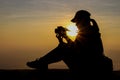 Silhouette of a woman holding a camera taking pictures outside during sunrise or sunset Royalty Free Stock Photo