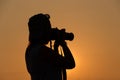 Silhouette of a woman holding camera taking pictures outside during sunrise or sunset Royalty Free Stock Photo