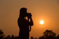 Silhouette of a woman holding camera taking pictures outside during sunrise or sunset Royalty Free Stock Photo