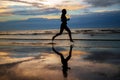 Silhouette of woman jogger running on sunset beach with reflection Royalty Free Stock Photo