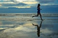 Silhouette of woman jogger running on sunset beach with reflection Royalty Free Stock Photo