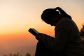 Silhouette of woman kneeling down praying for worship God at sky background. Christians pray to jesus christ for calmness. In Royalty Free Stock Photo